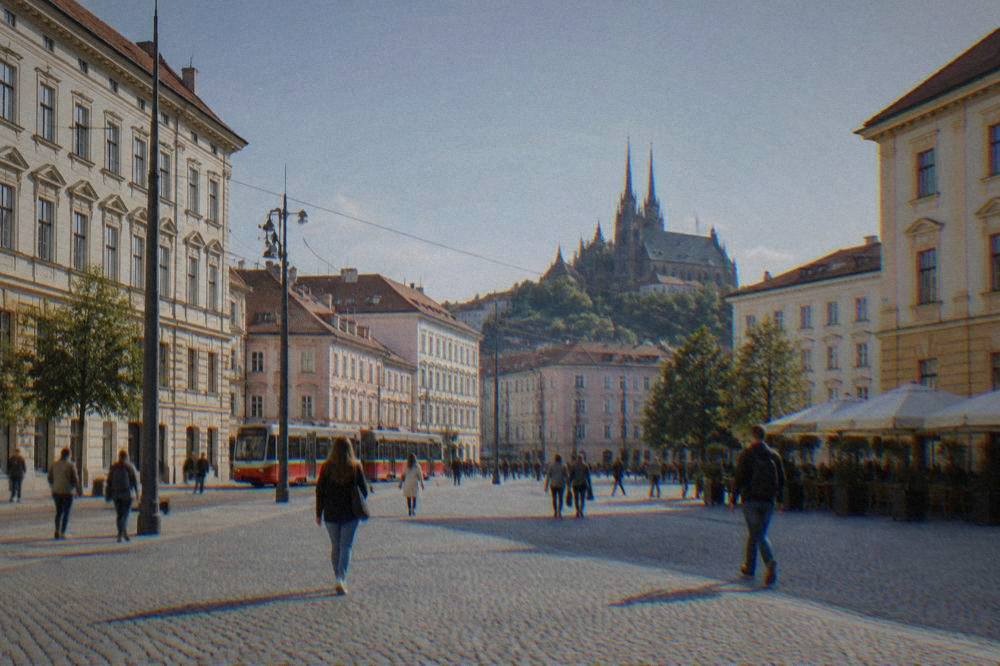 Pedestrians crossing a cobblestone square with historic facades in central Brno