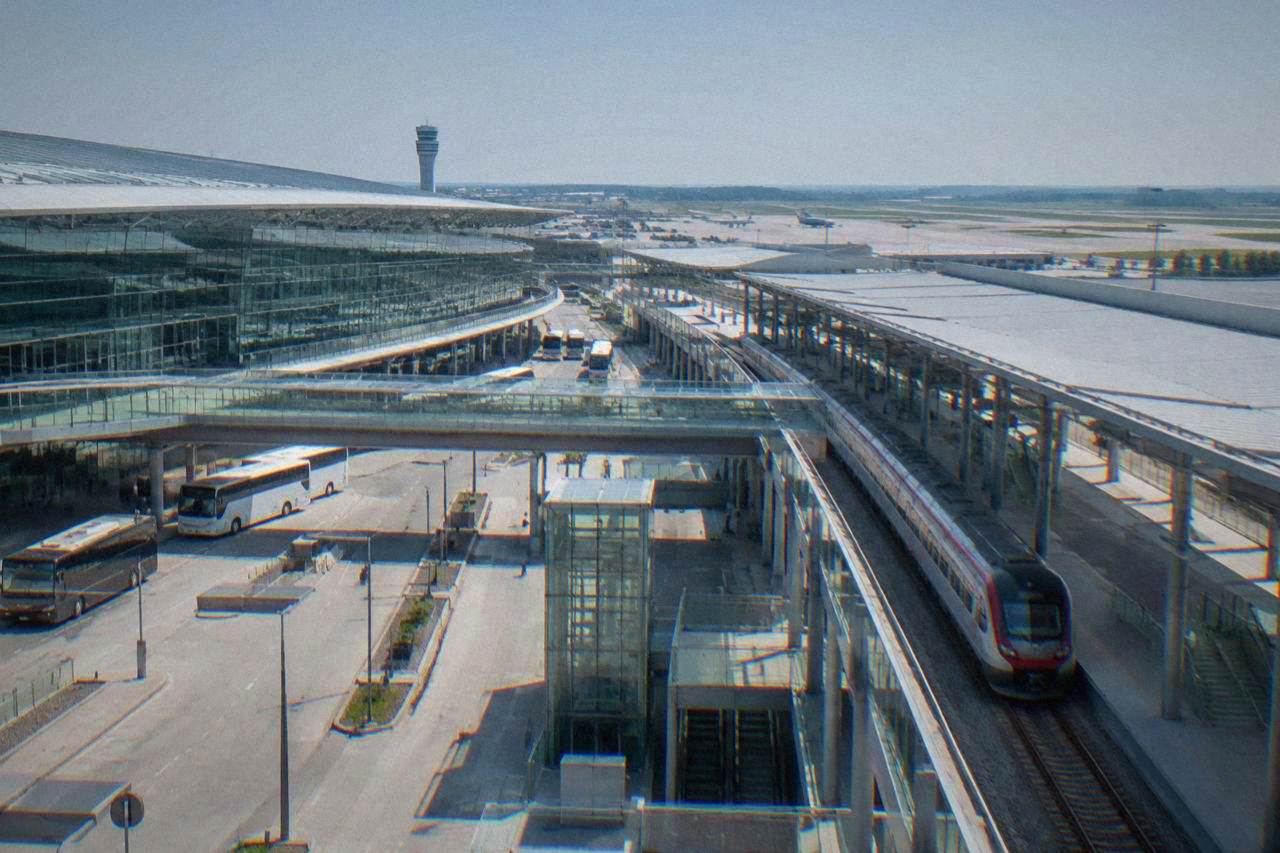 A long-distance train waiting at a platform inside a modern airport railway station