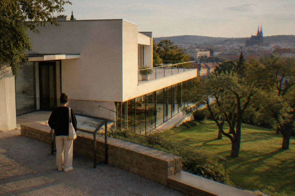 Visitor reading an information panel beside a modernist villa entrance