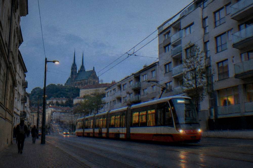 A tram passing modern apartment buildings on a Brno street