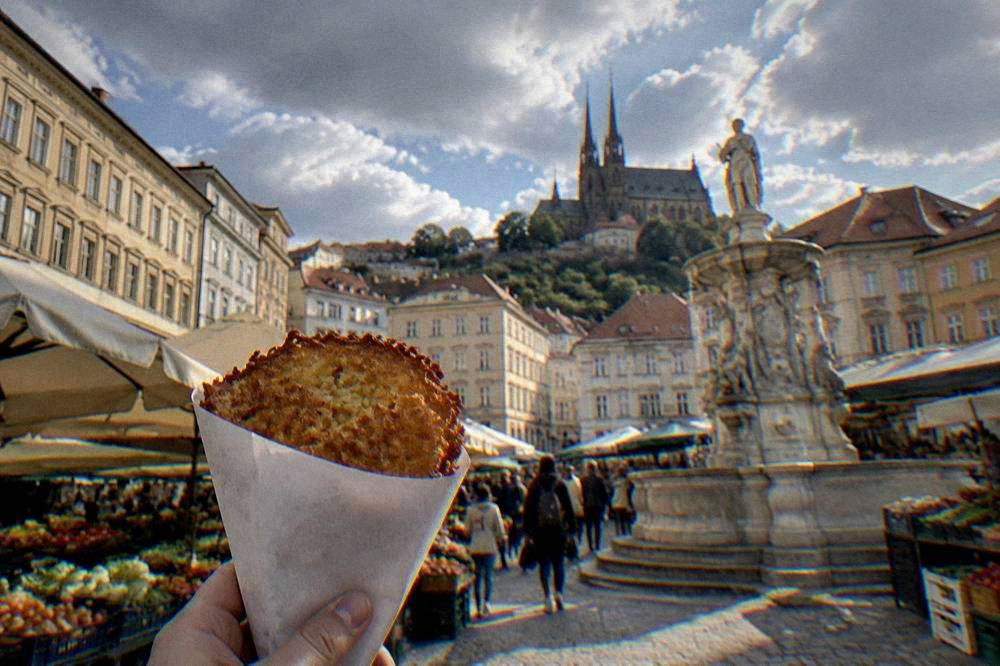 A paper cone holding a hot fried potato pancake at a market stall