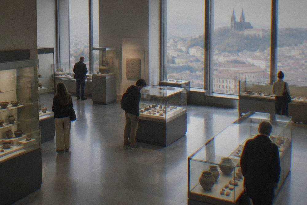 Interior of a Brno museum hall with visitors looking at glass display cases on a grey day