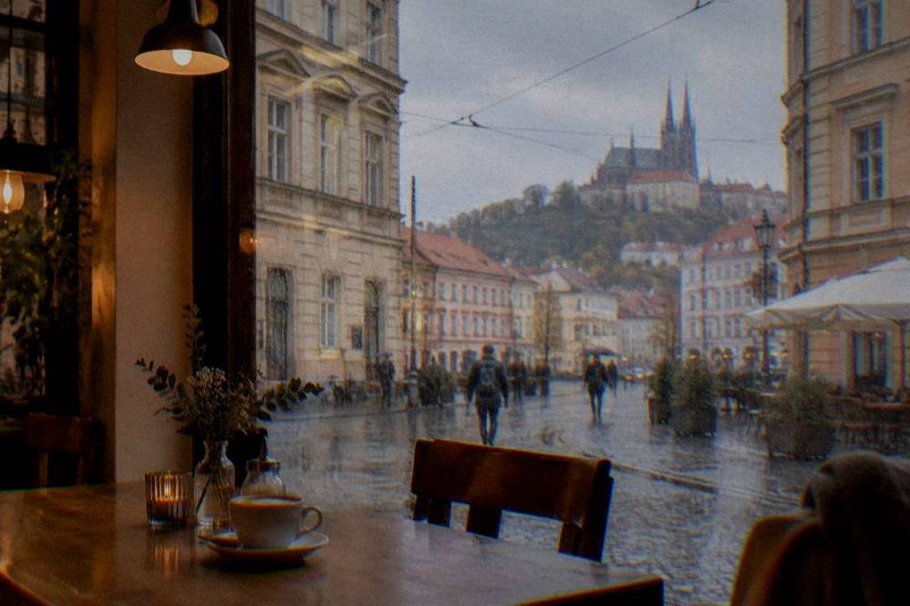 Cozy café interior in Brno with rain streaked windows, wooden tables and warm lighting
