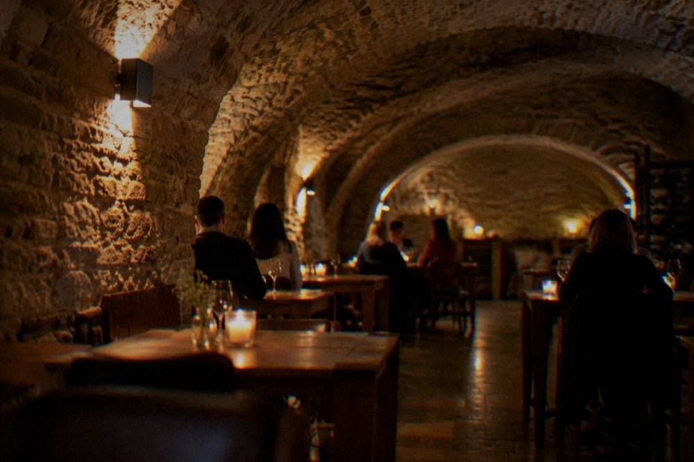 Evening restaurant cellar in Brno with candles on wooden tables and vaulted stone ceiling