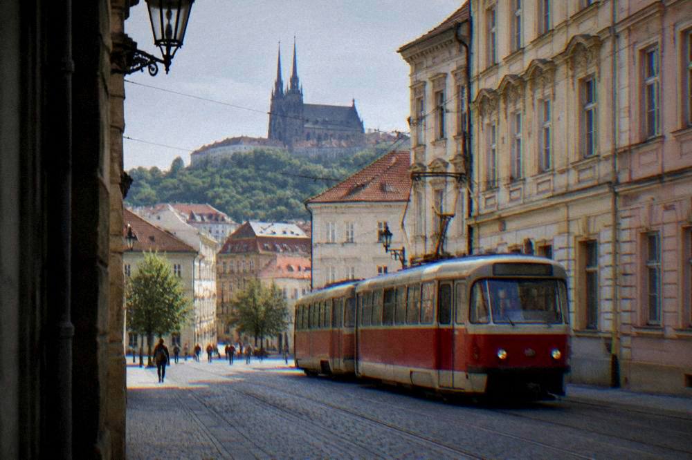 A red Brno tram passing historic facades on a street in the city centre