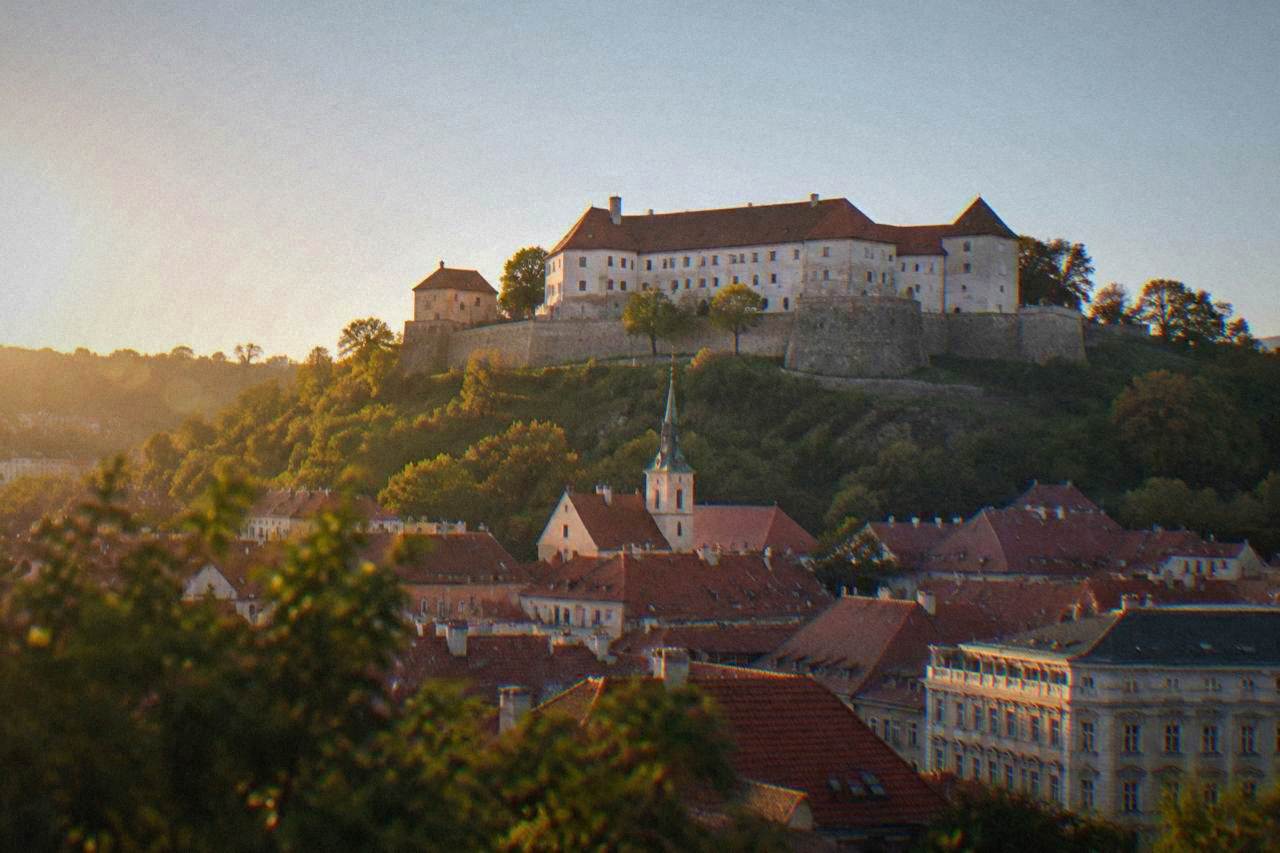 Špilberk Castle walls rising above the red rooftops of Brno under a clear sky