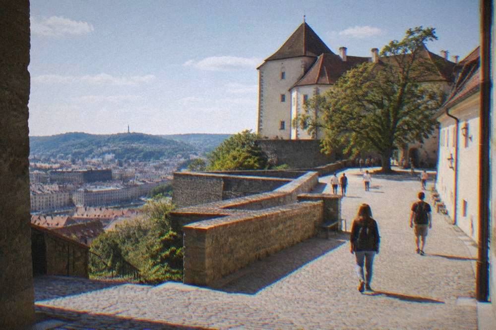 Visitors walking the stone courtyard and ramparts of Špilberk Castle on a bright morning