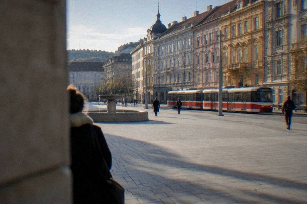 A red Brno tram passing ornate facades on a street near Freedom Square