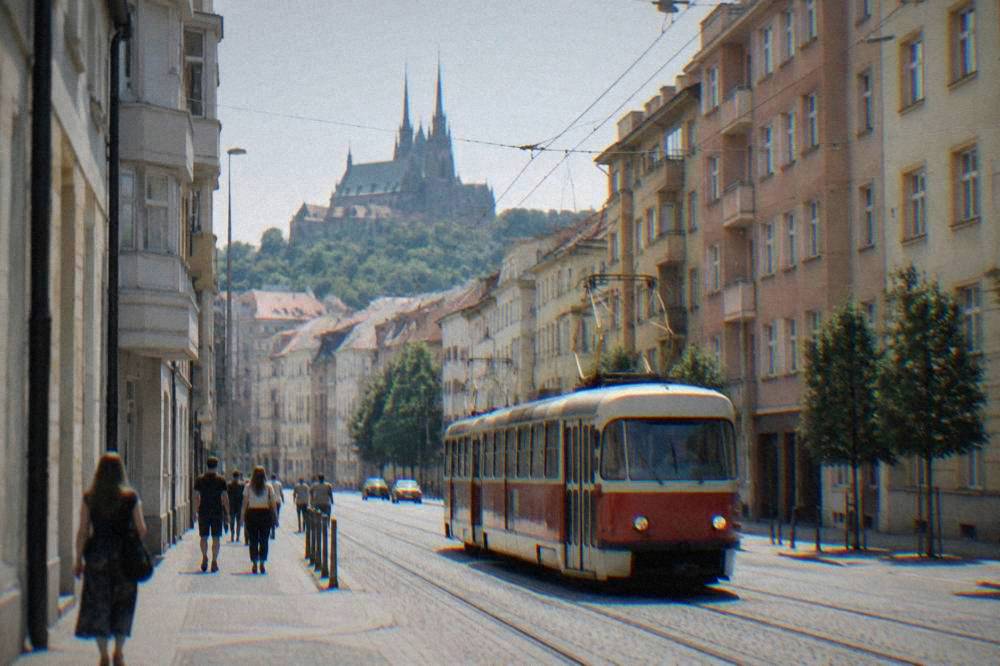 A red and cream tram moving along a Brno street lined with twentieth-century apartment buildings