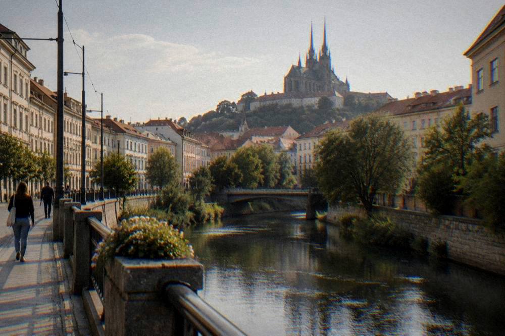 The spires of a cathedral on a hill rising above the rooftops of Brno in evening light