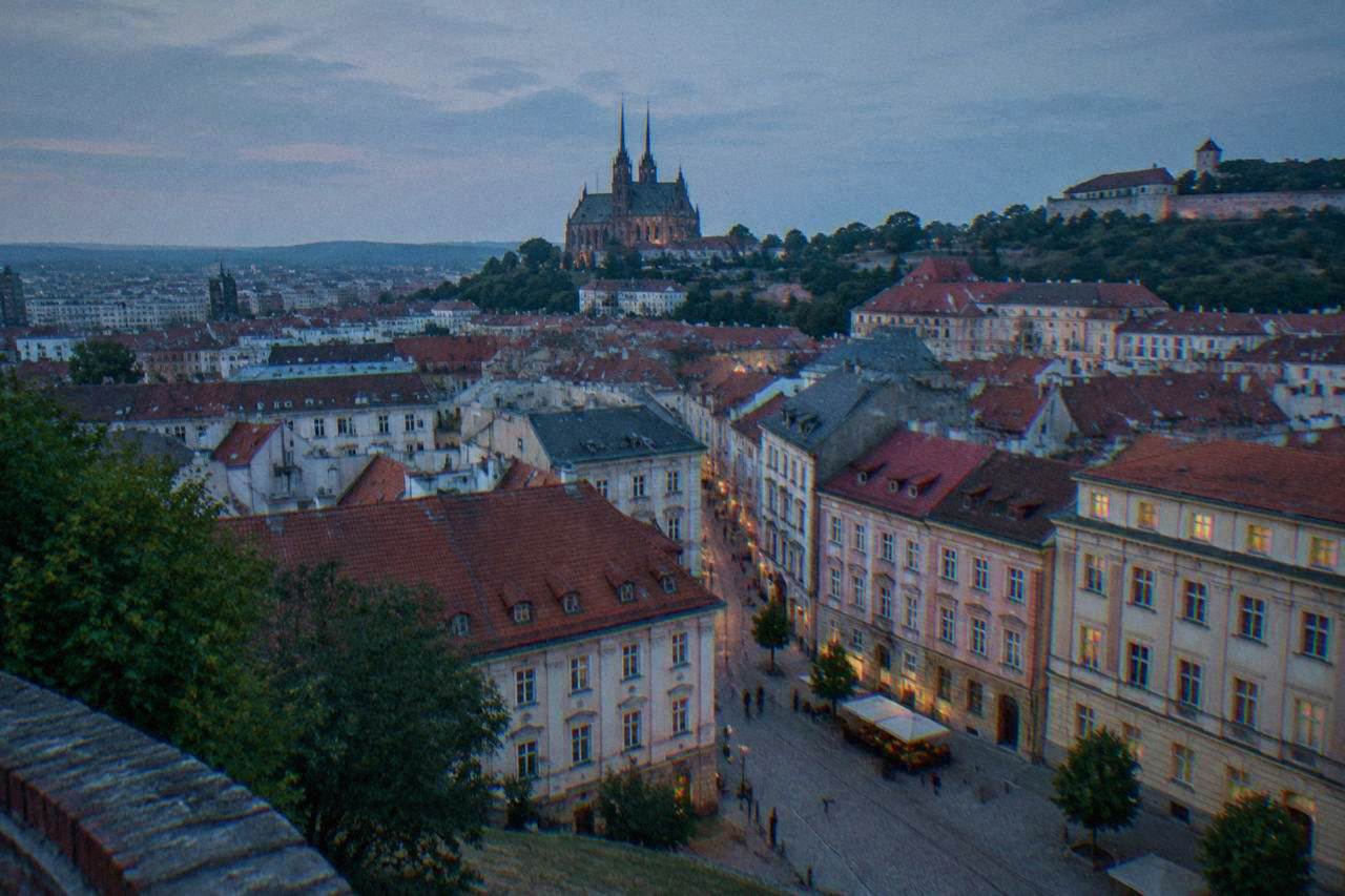 Brno old town rooftops seen from a hill with castle walls on the horizon