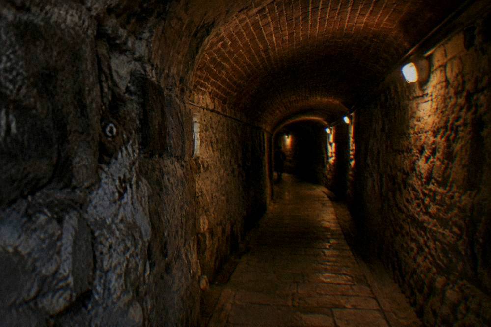 Rough-hewn concrete and rock tunnel of a Cold War era bunker lit by lamps