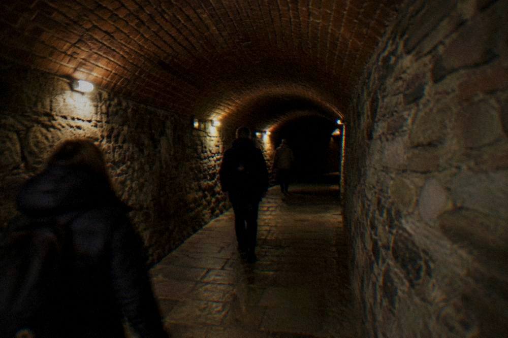 Visitors in jackets walking through an illuminated historic tunnel attraction