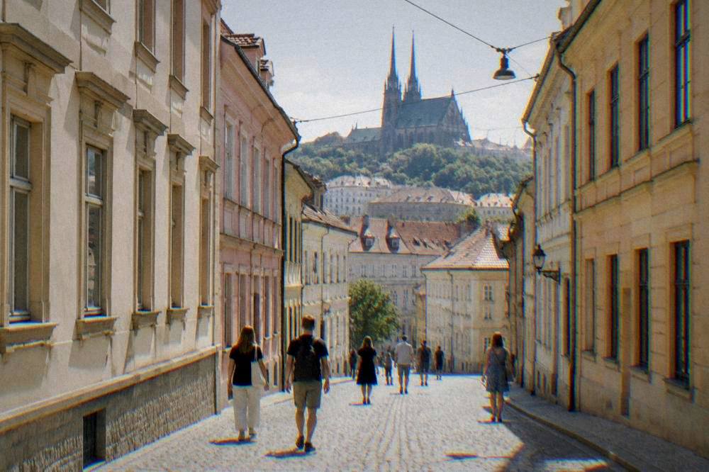 Visitors walking along a cobbled lane between pastel townhouses in central Brno