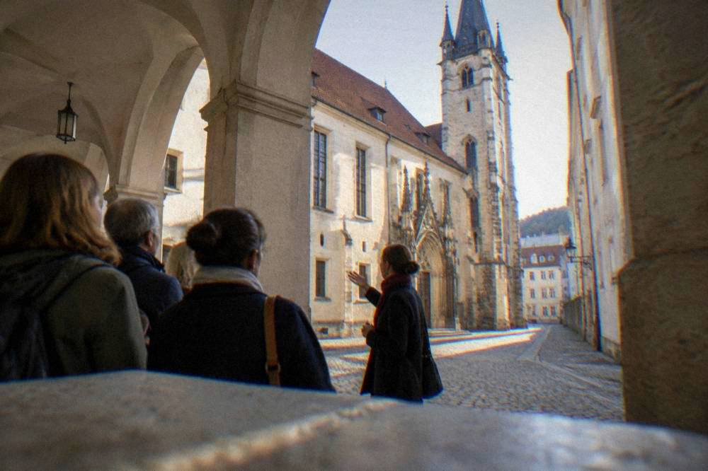 A tour guide describing the old town hall to a small group in a Brno arcade