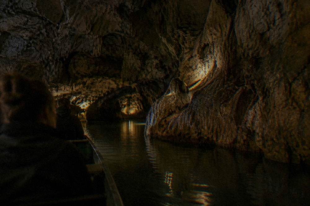 Boat on an underground river inside a dimly lit limestone cave passage
