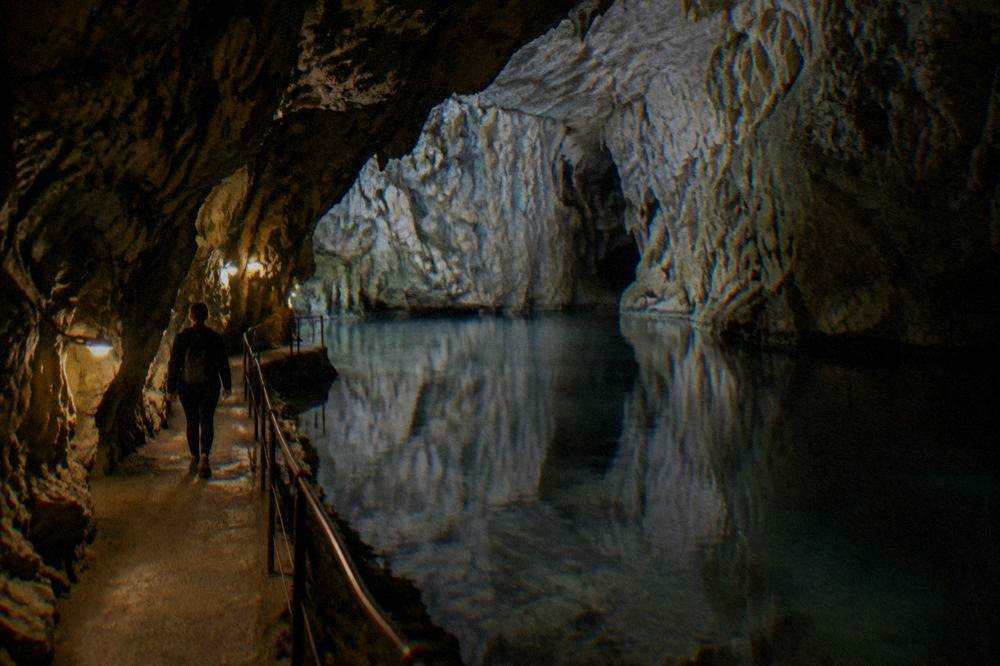 An underground cave lake reflecting limestone walls in the Moravian Karst